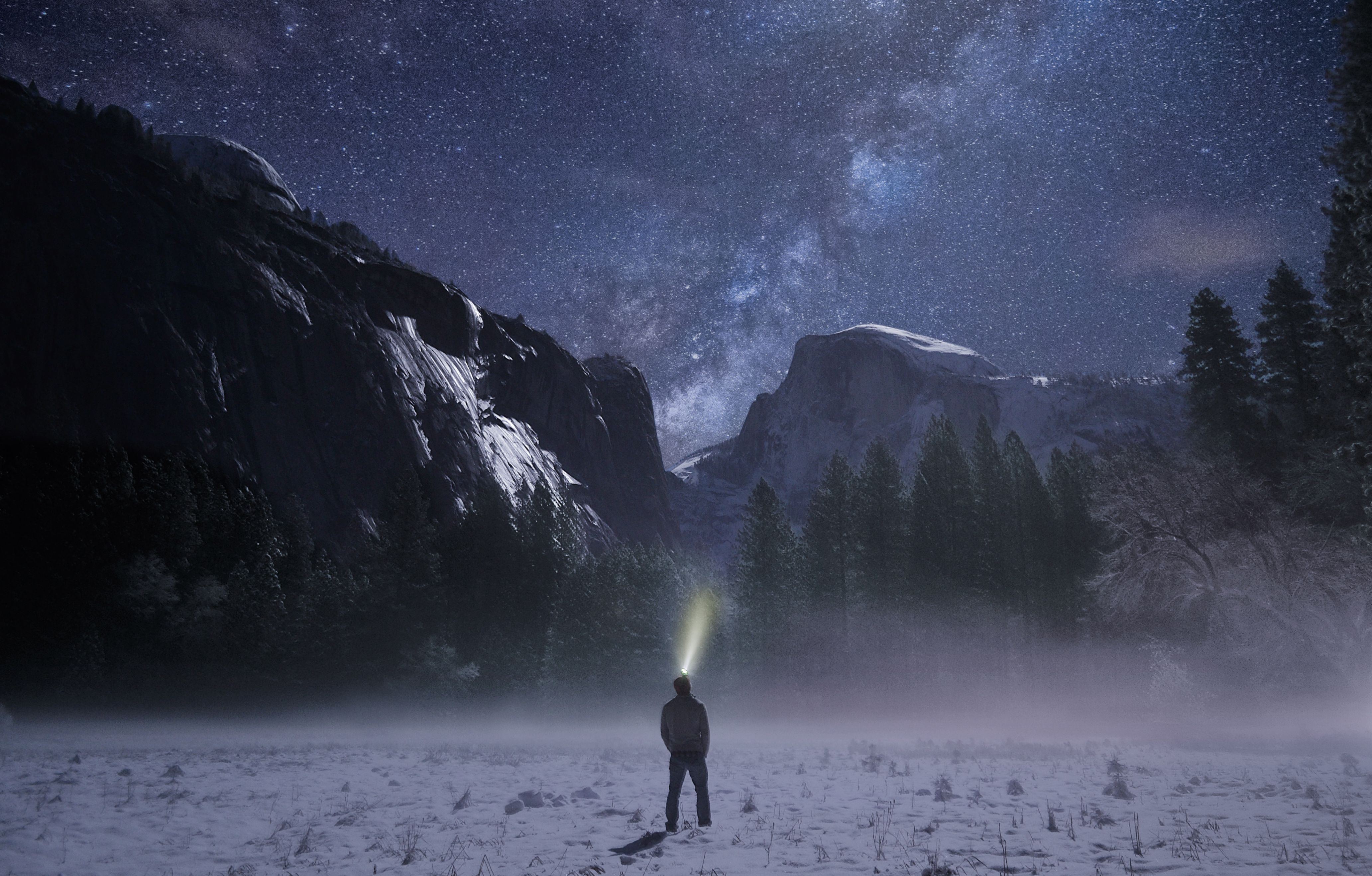 Explorateur nocturne avec lampe frontale dans une vallée enneigée